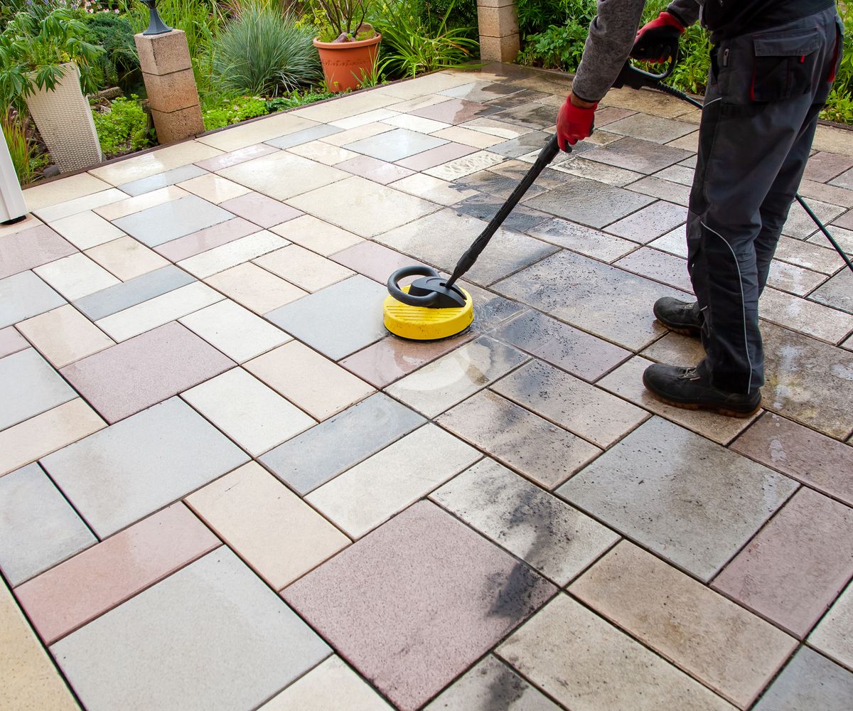 Cleaning stone slabs on patio with the high-pressure cleaner.